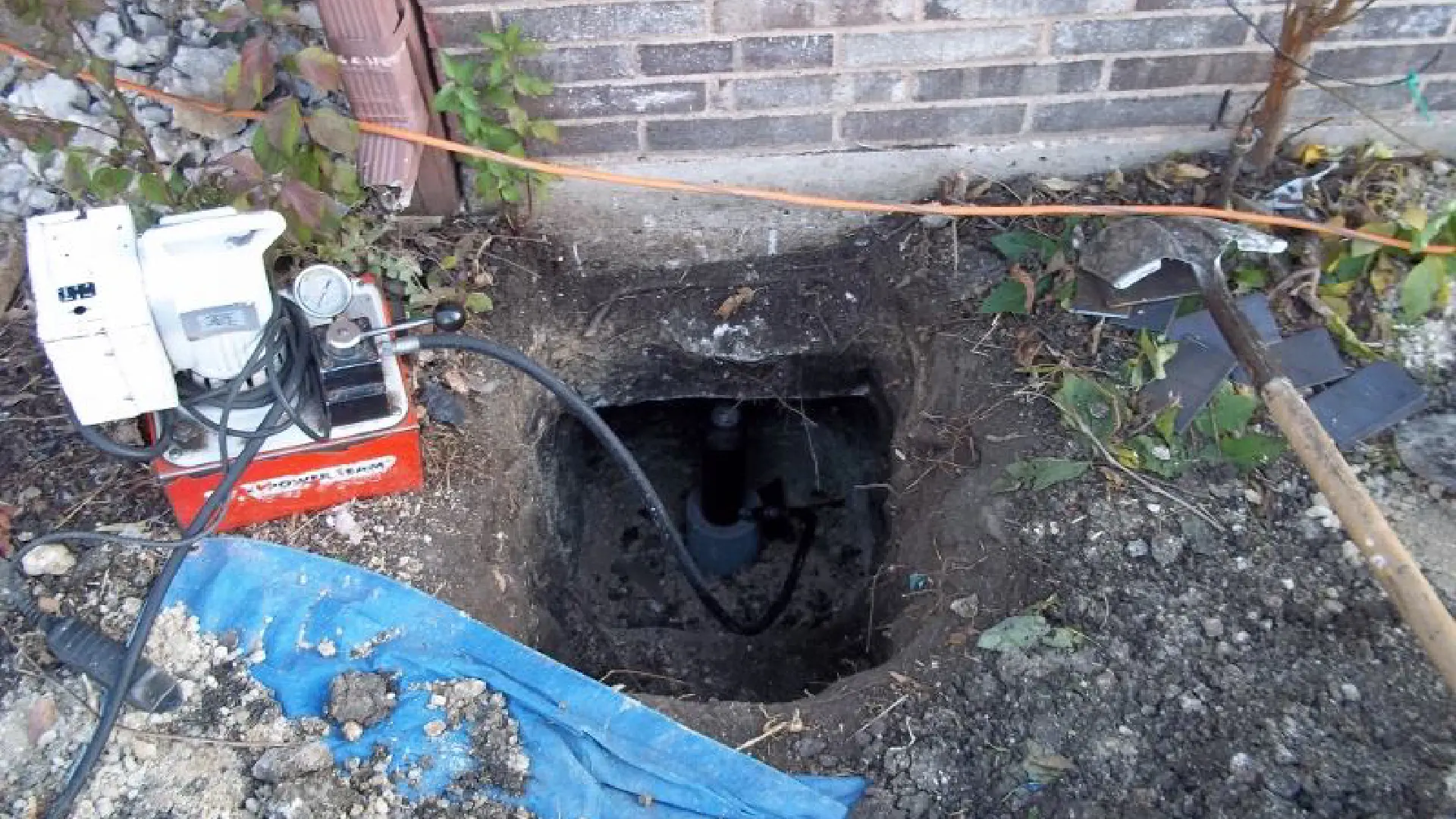 A hole in the ground with wires and cables around it.