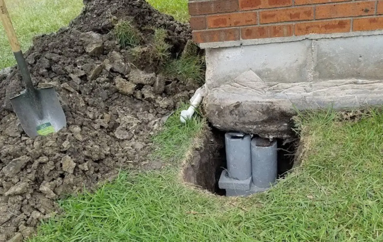 A hole in the ground with two pipes sticking out of it.
