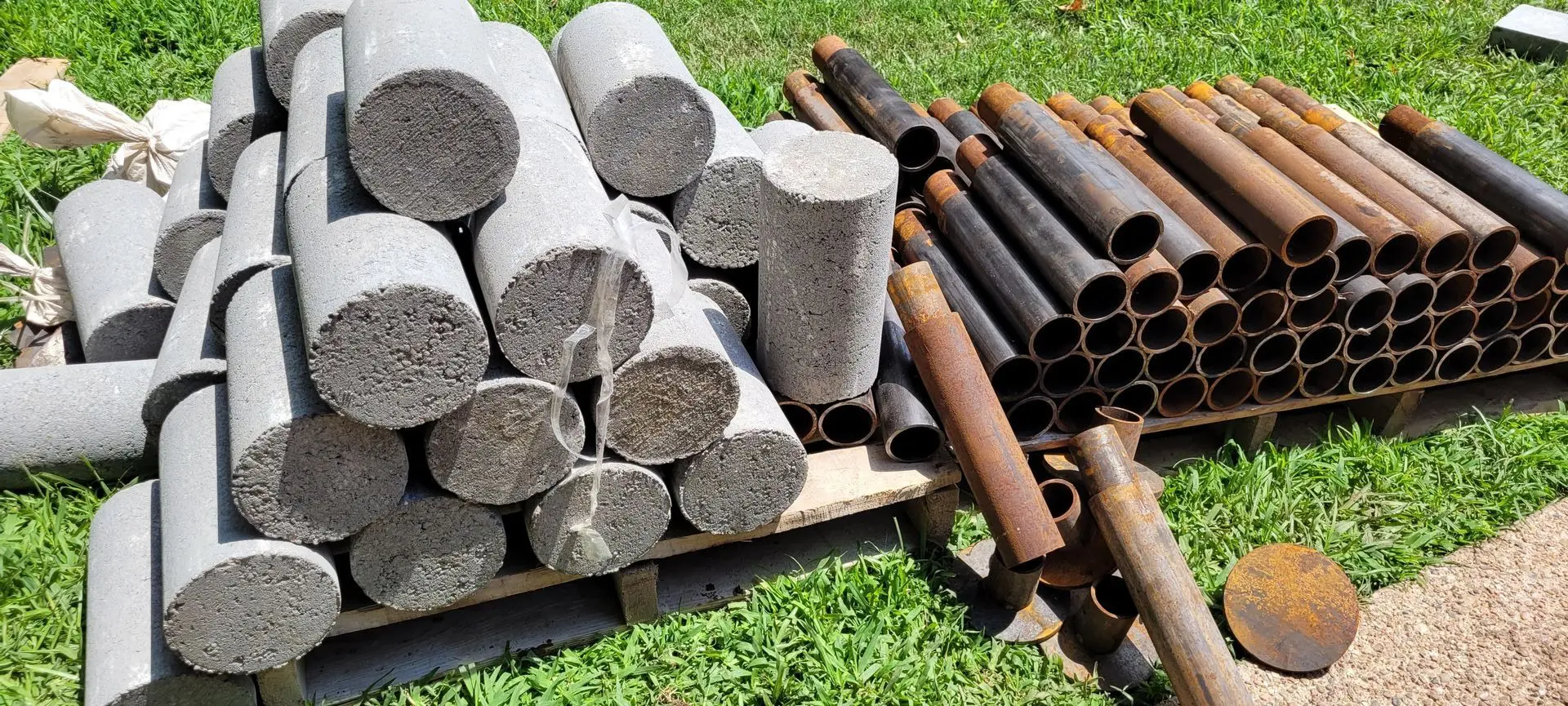 steel hybrid pier system materia A pile of concrete and metal pipes sitting on top of grass.