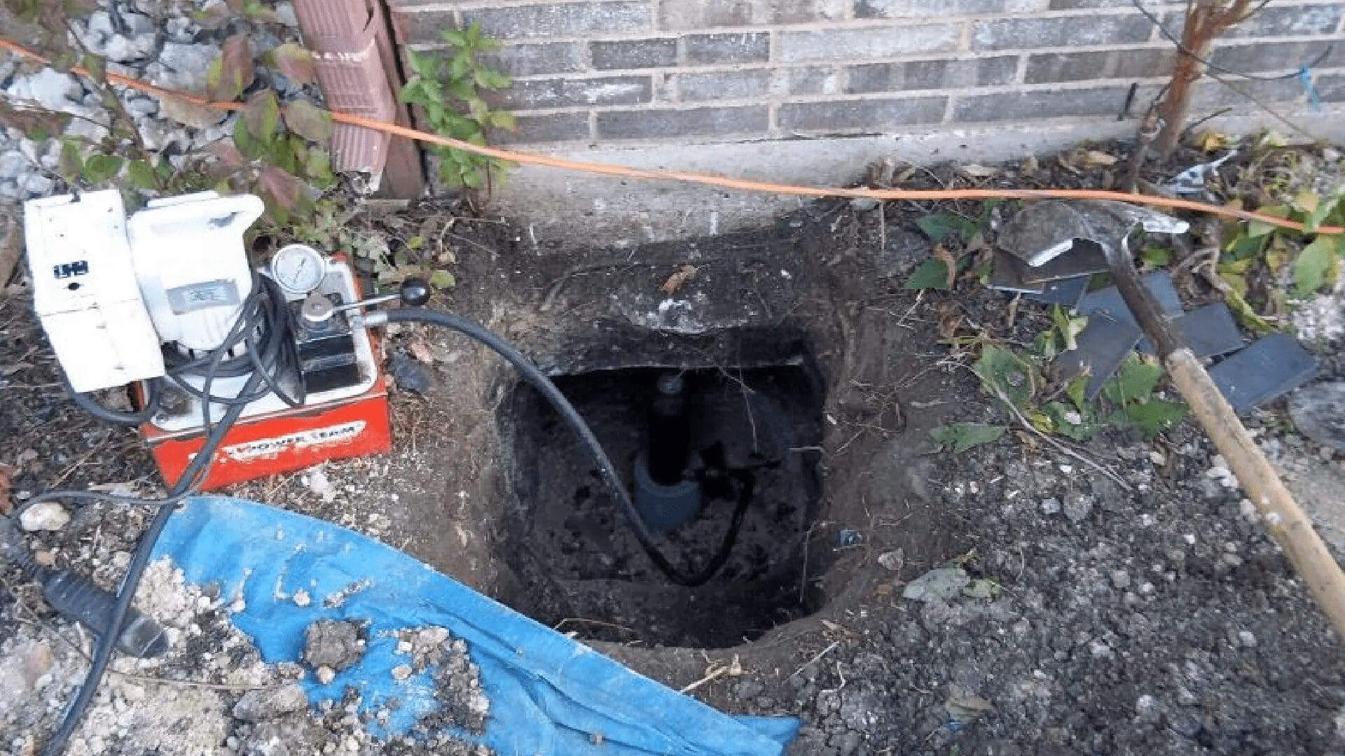 Sinkhole in backyard revealing damaged water pipes and meter under concrete debris